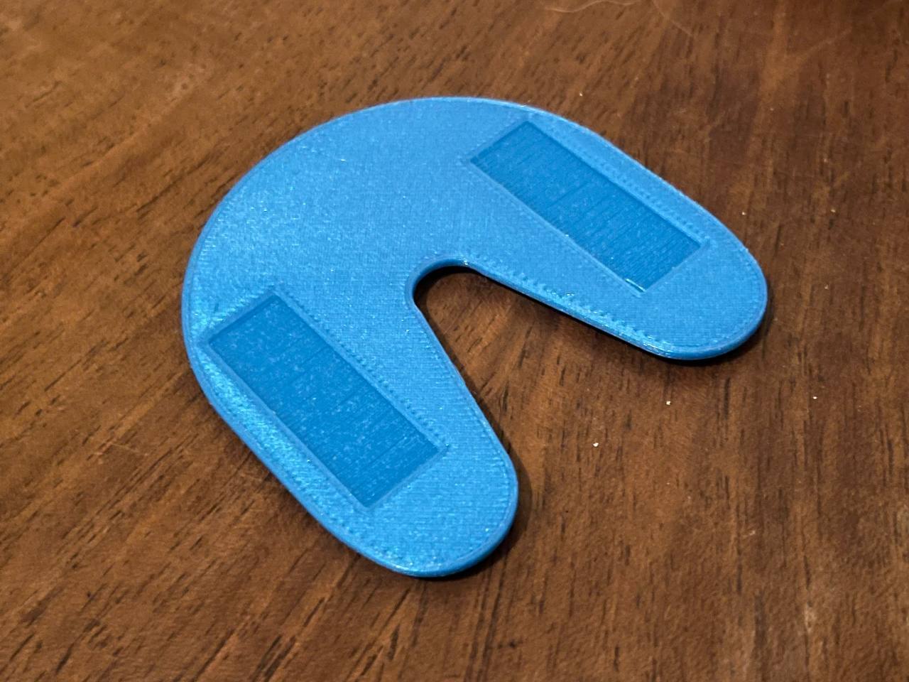 le dessous de l'objet imprimé en 3D, on voit 2 surfaces moins lisses pour faciliter le grip lors de l'usage